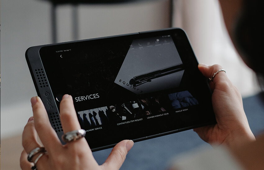 Person holding a tablet showing sleek hotel services like contactless requests and gear loans.