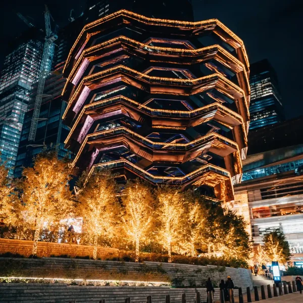 Honeycomb-style structure lit in warm gold with string lights and glowing trees below.