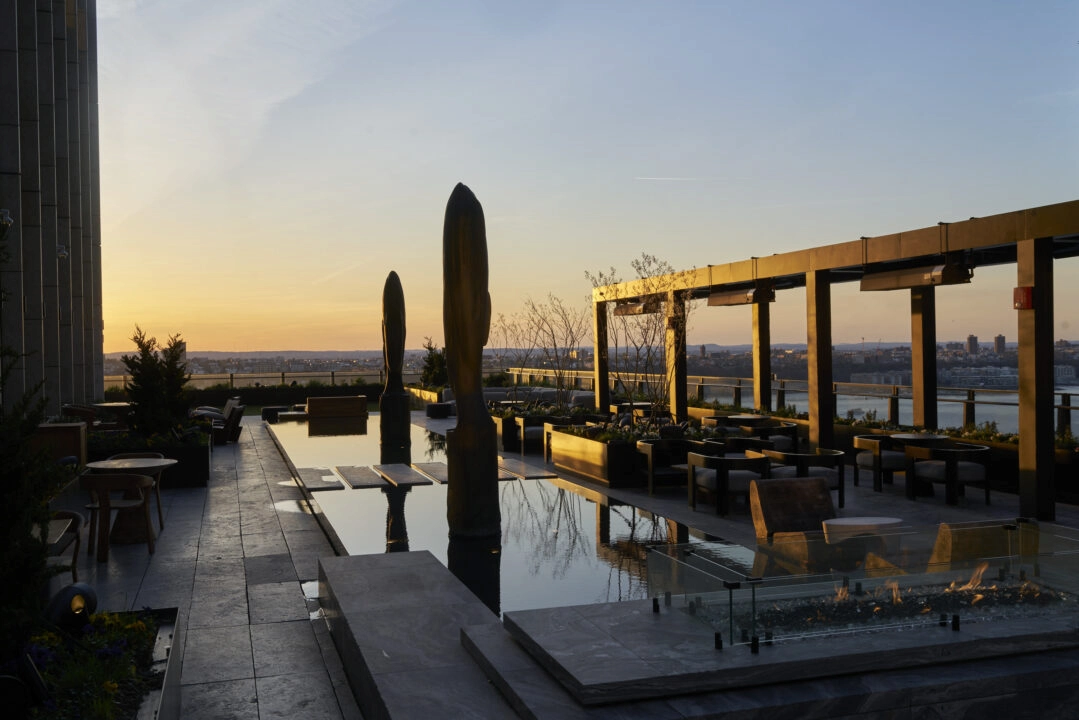 Equinox rooftop terrace at sunset with water feature, sculptural elements, fire pit, pergola and city view