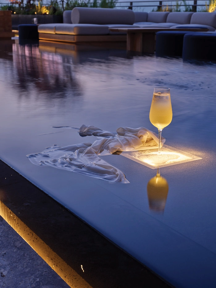 Champagne flute on lit surface with white cloth in elegant outdoor lounge at twilight