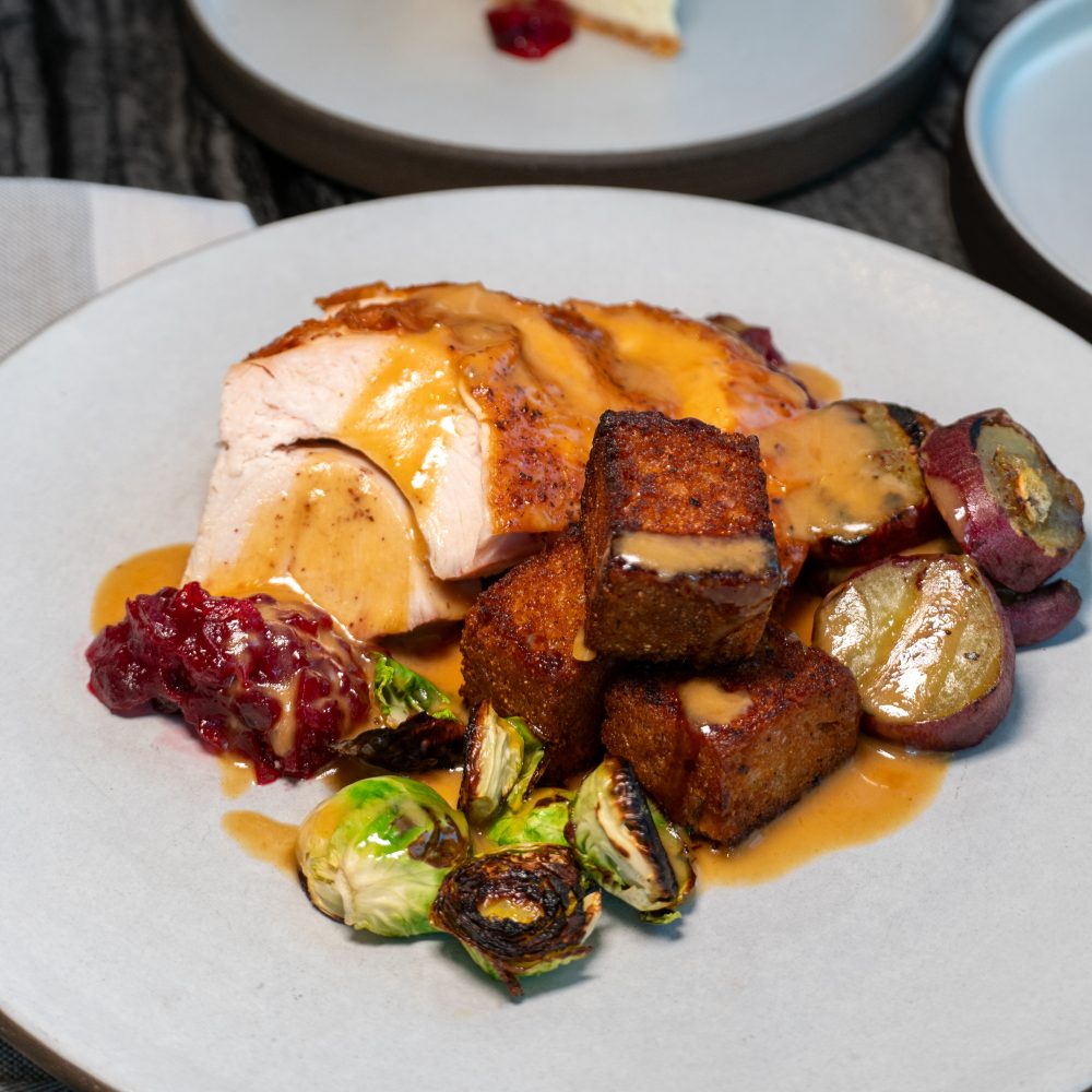 Roasted turkey with gravy, stuffing, Brussels sprouts, purple potatoes and cranberry sauce on light plate