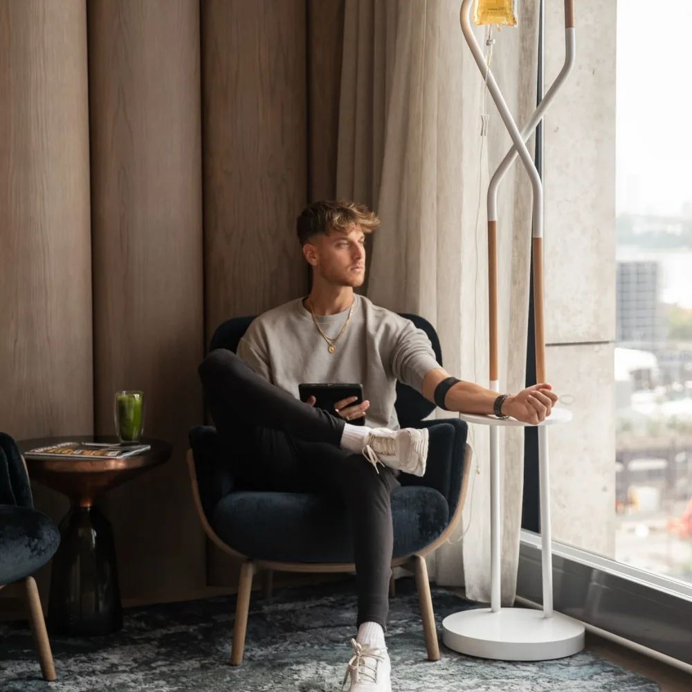 NutriDrip IV therapy session at Equinox Hotel with guest seated by window receiving wellness infusion in luxury setting