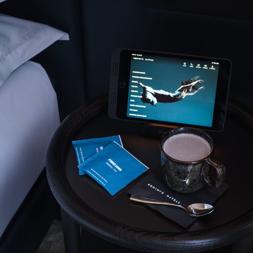 Tablet, mug, and collagen packets on bedside table in Equinox Hotel wellness-focused room setup