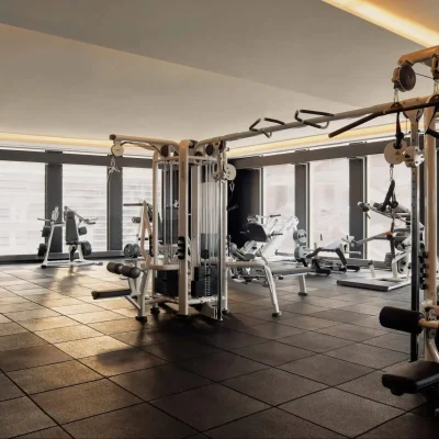 Bright, modern gym with strength and cardio machines, rubber flooring, and floor-to-ceiling windows