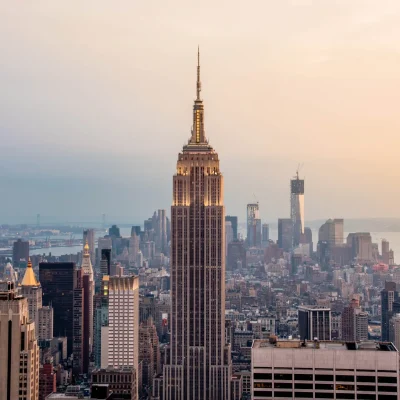 Empire State Building centered in Manhattan skyline at sunset with warm light and distant Hudson River