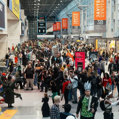 New York Comic Con crowd at Javits Center with cosplay attendees, orange banners, and pop culture displays