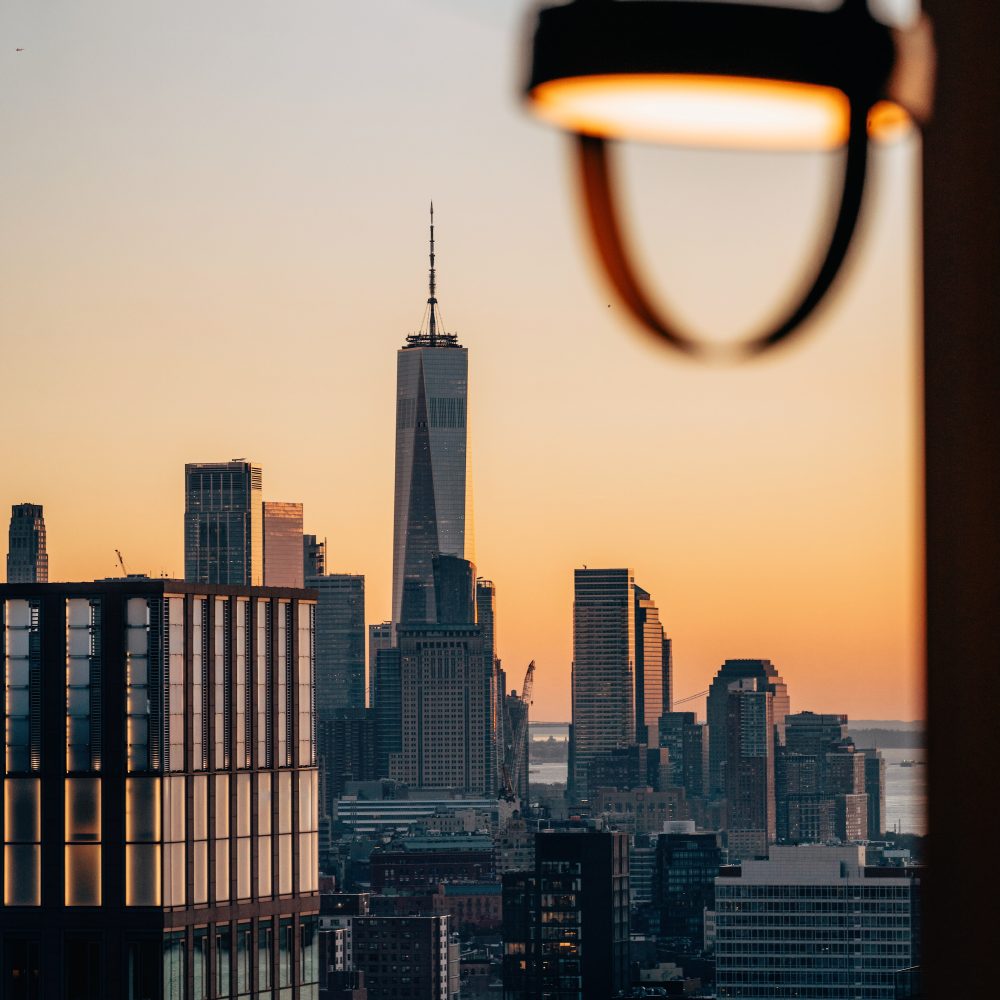 Skyline of Lower Manhattan at sunset with One World Trade Center rising above the city.